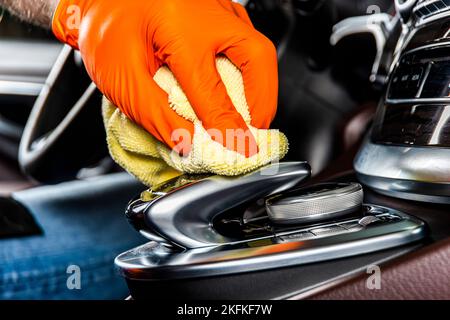 Un uomo pulisce i pannelli interni e il cruscotto dell'auto con un panno in microfibra giallo. Dettagli dell'auto o concetto di valeting. Messa a fuoco selettiva. Dettagli auto. Pulizia Foto Stock