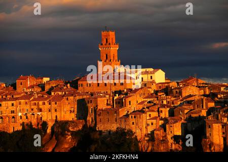 Primo piano e dettaglio della città medievale Pitigliano che illumina alla luce della sera la cattedrale Santi Pietro e Paolo e la torre nel centro, Maremma, Provin Foto Stock