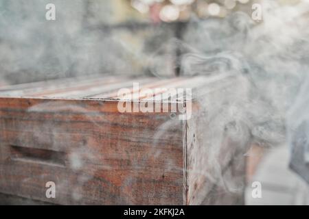 Fumo, scatola di legno e fattoria di api o sfondo agricolo per apicoltura e apiarista all'aperto per miele, favo o cibo. Bee fumatore, attrezzature Foto Stock