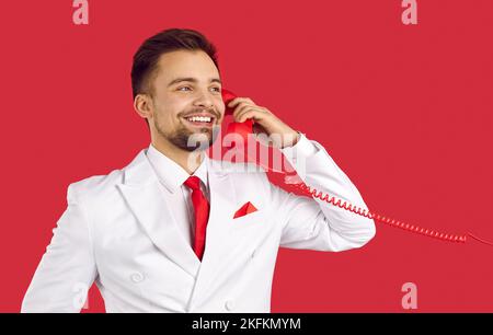 Un uomo sorridente parla sul telefono fisso Foto Stock