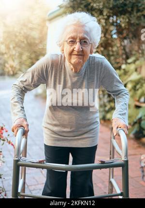 Ritratto, donna anziana e telaio a piedi al parco per la salute, il benessere e il sole sano. Libertà, pensionamento e anziana donna con disabilità Foto Stock