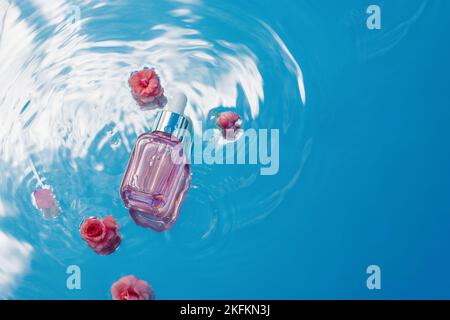 Fondo acqua blu con increspature e bottiglia cosmetica con rose rosa. Concetto idratante e di cura della pelle con acido ialuronico Foto Stock