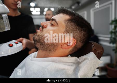 ISTANBUL, TURCHIA - 16 MAGGIO 2022: Uomo cliente seduto nel barbiere di Esenyurt, Istanbul Foto Stock