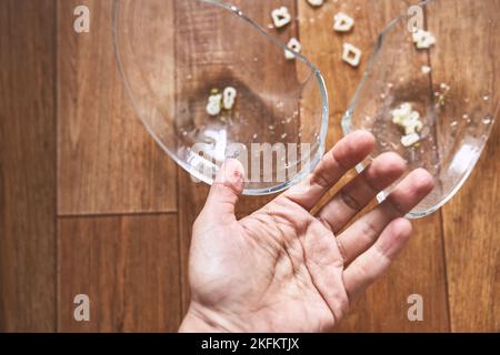 Primo piano di un dito femmina tagliato sullo sfondo di una tazza divisa. Una mano con il sangue ricevuto durante la pulizia dei piatti rotti. Foto di alta qualità Foto Stock