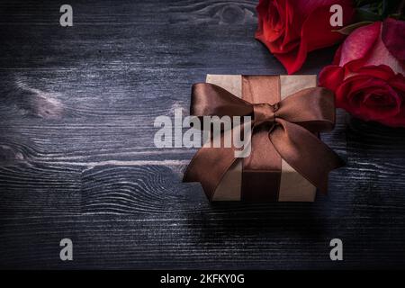 Rose rosse fiorite scatola regalo su concetto di vacanza sfondo in legno. Foto Stock