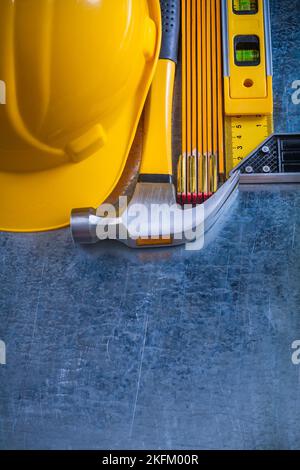 Casco da costruzione martello in legno metro prova quadrato e livello di costruzione su graffiato sfondo metallico concetto di manutenzione. Foto Stock