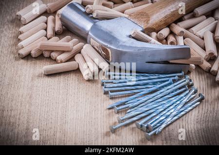 Composizione di tasselli in legno chiodi metallici e martello da artiglio. Foto Stock