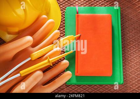 Elmetto da costruzione per notebook per elettricisti guanti tester elettrico su tappetino dielettrico. Foto Stock