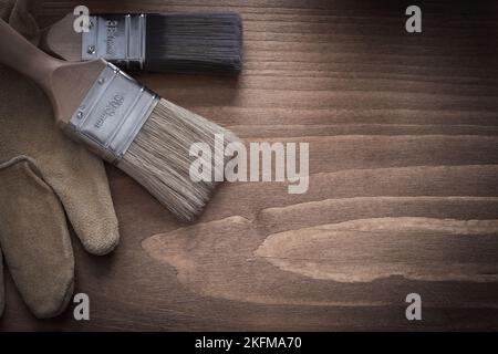 Pennelli e guanti di protezione marroni in pelle su superfici in legno vintage. Foto Stock