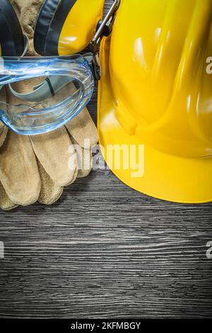 Guanti protettivi occhiali cuffie elmetto su tavola di legno. Foto Stock