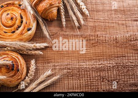 Panetti di uva passa maturi alle orecchie di grano croissant su tavola di legno di legno di legno di ovino concetto di cibo e bevande Foto Stock