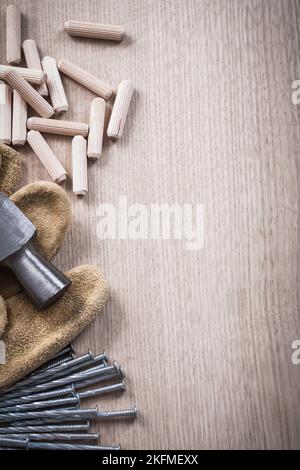 Pila di tasselli in legno martello a artiglio guanti protettivi in pelle e chiodi in metallo su legno tavola vista ravvicinata costruzione concetto. Foto Stock