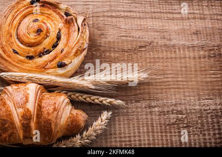 L'uva passa delle spighe di grano pancia croissant su tavola di legno di quercia concetto di cibo e bevande Foto Stock