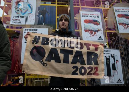 Berlino, Germania. 19th Nov 2022. Gli attivisti si sono riuniti a Berlino il 19 novembre 2022 per richiamare l'attenzione sulle violazioni dei diritti umani in Qatar. Gli attivisti del gruppo Extinction Rebellion hanno bloccato l'ingresso del negozio ammiraglia Adidas su Tauentzienstrasse per protestare contro la sponsorizzazione della Coppa del mondo. Un banner che legge ''#BoycottQatar2022'' ha invitato il pubblico a non acquistare alcun prodotto dalla Coppa del mondo in Qatar, come la palla ufficiale Adidas match, e a non guardare le partite. Con la Coppa del mondo in Qatar, massicce emissioni di fossili, violazioni dei diritti umani e la morte del lavoratore ospite Foto Stock