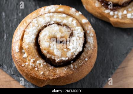 Panini alla cannella su tavolo di legno. Dessert svedese Kanelbule Foto Stock