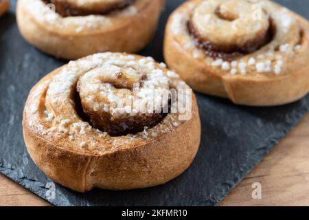 Panini alla cannella su tavolo di legno. Dessert svedese Kanelbule Foto Stock