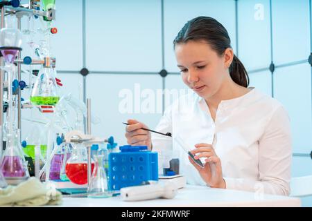 analisi del suolo dalla zona di guerra per prodotti chimici giovane assistente di laboratorio donna prende campioni di suolo per analisi chimiche Foto Stock