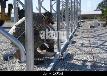 Master Sgt. Jack Fergen stringe un cavo del tenditore collegato ad una struttura di tessuto in fase di costruzione per la scuola superiore di Woodbine, Iowa, il 28 settembre 2022. Ai militari dello squadrone di ingegneria civile della Guardia Nazionale dell'aria dell'Iowa 185th è stato chiesto di contribuire a costruire la struttura donata che sarà utilizzata per ospitare i viaggi personali DOD a Woodbine, partecipando a un innovativo progetto di formazione per la preparazione nei prossimi mesi. U.S. Air National Guard foto Senior Master Sgt. Vincent De Groot Foto Stock