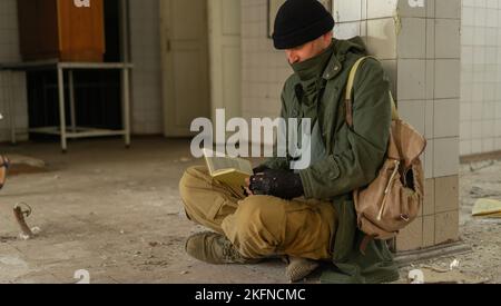 Sopravvissuto alle catastrofi nucleari in un ambiente post apocalittico, indossa una maschera bandana e legge un libro. Disastro ambientale e inquinamento atmosferico con Foto Stock