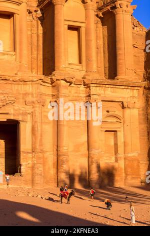 Petra, Giordania - 3 novembre 2022: Persone, asino al monastero di ad Deir nella città antica, vista panoramica al tramonto, sito patrimonio dell'umanità dell'UNESCO Foto Stock