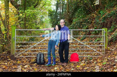 Coppia che riposa contro il cancello del bosco in autunno Foto Stock