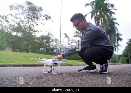 un giovane uomo sta gestendo un drone in mezzo alla strada. Giovane uomo che tiene il drone prima del volo. Foto Stock