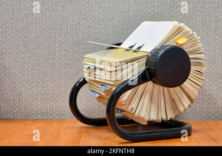 Organizzatore di file Rolodex seduto su una scrivania da ufficio, vista angolata con divisorio grigio dietro. Foto Stock