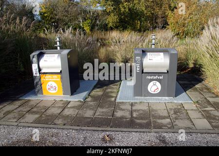 Separazione dei rifiuti nei Paesi Bassi con contenitori interrati separati per plastica, lattine, contenitori per bevande e rifiuti residui. Autunno, erba alta, alberi, stagno. Foto Stock