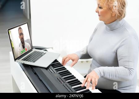 Musicista giovane e grazioso che suona il pianoforte digitale classico a casa durante la lezione online a casa, distanza sociale durante la quarantena, autoisolamento, online Foto Stock