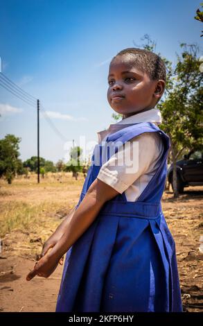 Una giovane ragazza in divisa scolastica in Malawi guarda avanti in modo assertivo Foto Stock