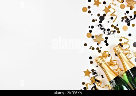 Capodanno bordo laterale di oro e nero confetti, streamers e champagne. Vista dall'alto su sfondo bianco. Foto Stock