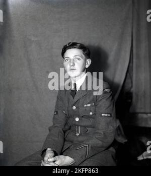 Circa 1949, storico, presso RAF Tern Hill, Market Drayton, Shropshire, Inghilterra, Regno Unito, un giovane, un Junior NCO seduto dentro per la sua foto. Il suo abito da servizio o uniforme è realizzato in Barathea, un tradizionale tessuto di lana pettinata, più liscio dell'uniforme pesante e spessa di lana di un aviatore. Sul braccio inferiore sinistro della sua tunica, un'insegna a freccia rivolta verso l'alto, che era una RAF Good Conduct Stripe, al centro della tunica, appena sopra il gomito, un emblema a elica, che denota un Aircraftman leader e sulla parte superiore del braccio, un RAF Shoulder Flash. Foto Stock