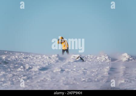 Donna in mantello giallo soffre di venti invernali islandesi Foto Stock