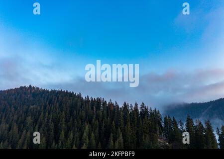 Montagna paesaggio atmosferico di alte montagne in fitta nebbia in tempo piovoso, panorama di cime di montagna in fitte nuvole, alba in montagna in ea Foto Stock