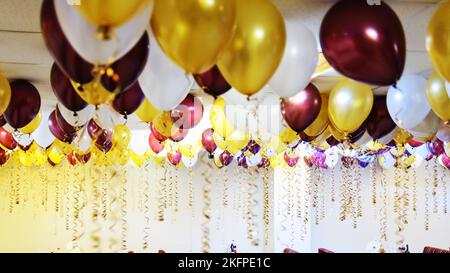 Palloncini colorati appendono sotto il soffitto bianco nel cafe' Foto Stock