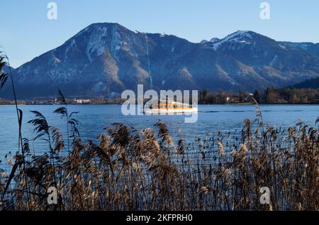 Piccola nave illuminata dal sole sul lago alpino Tegernsee con le sue acque turchesi trasparenti nella valle Tegernsee nelle Alpi Bavaresi contro il cielo blu Foto Stock