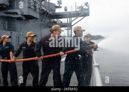 YOKOSUKA, Giappone (ott 3, 2022) – i marinai USS Blue Ridge (LCC 19) utilizzano una manichetta antincendio durante l'addestramento di valutazione MOB-D (Mobility Damage Control Warfare) a bordo della nave ammiraglia della flotta statunitense 7th, 3 ottobre 2022. Le valutazioni MOB-D sono una serie di esercitazioni volte a valutare la capacità di una nave di rispondere alle emergenze e mantenere la nave a galla in situazioni di emergenza. Blue Ridge è la più antica nave operativa della Marina militare e, come la 7th Fleet Command ship, lavora attivamente per promuovere le relazioni con alleati e partner nella regione di Indo-Pacifico. Foto Stock