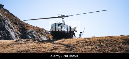 Un soldato dell'Esercito italiano con la Brigata Alpini salta da un elicottero UH-60 Blackhawk per attaccare un obiettivo durante un esercizio di fuoco in bianco accanto ai paracadutisti dell'Esercito USA assegnati a 2nd battaglione, 503rd reggimento di fanteria paracadute come parte dell'esercizio Summer Resolve nella Provincia di Bolzano, Italia, 3 ottobre 2022. Exercise Alpine Star è un esercizio annuale di addestramento in montagna e artico organizzato dall'Esercito Italiano, multinazionale e multifase. I paracadutisti della ricognizione della Brigata Airborne 173rd si integrano all’interno di alcune aziende selezionate della Brigata Alpini dell’Esercito Italiano per imparare il techn Foto Stock