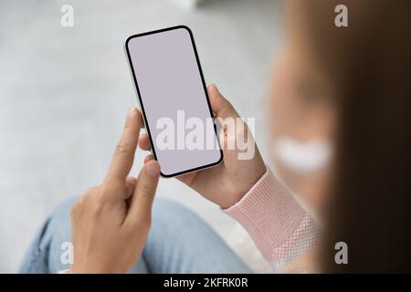 Donna che tiene in mano lo smartphone con schermo bianco mock-up, primo piano Foto Stock