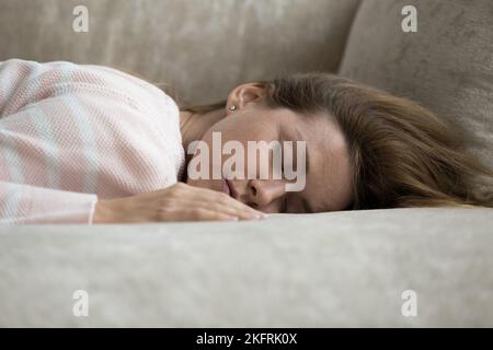 Giovane donna stanca che dorme a casa sdraiata sul divano Foto Stock