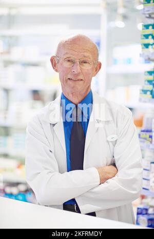 HES qui per aiutare con anni di esperienza. Ritratto di un farmacista anziano che lavora in un bancone. Foto Stock