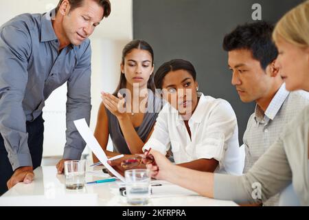 Sul punto di una svolta. Un gruppo di professionisti aziendali che discute di un documento. Foto Stock