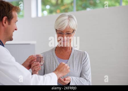 Sentirsi meglio con la medicina moderna. Un medico che consegna alcuni farmaci a un paziente anziano. Foto Stock