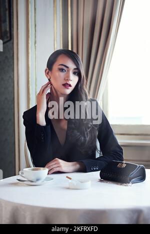 Poise classica. Ritratto di una giovane donna elegante con caffè e sigaretta. Foto Stock