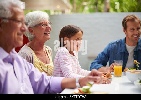 Godetevi una giornata in famiglia. Una famiglia felice multi-generazionale che ha un pasto insieme all'esterno. Foto Stock
