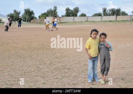 Ragazze come spettatori, uomini che giocano a calcio, insediamento della popolazione più povera al di fuori di Fes, Marocco, Africa Foto Stock