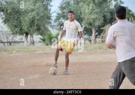 Uomini che giocano a calcio, insediamento della popolazione più povera al di fuori di Fes, Marocco, Africa Foto Stock