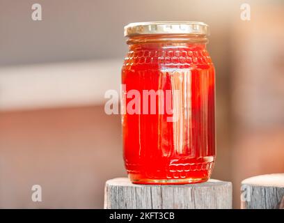 Miele, vasetto e fondo di vetro, alimentazione sana e produzione di zucchero da apicoltura, biologico e sostenibile dalla natura. Bottiglia per primo piano Foto Stock