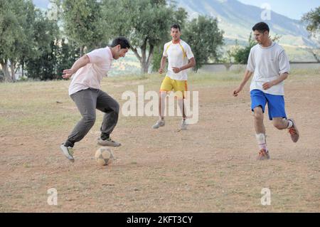 Uomini che giocano a calcio, insediamento della popolazione più povera al di fuori di Fes, Marocco, Africa Foto Stock