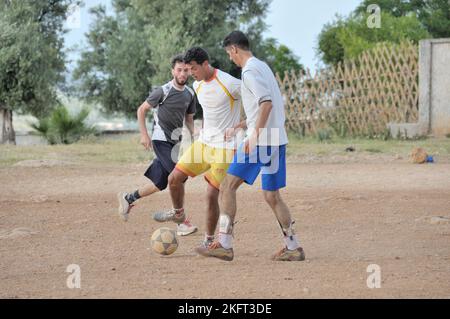 Uomini che giocano a calcio, insediamento della popolazione più povera al di fuori di Fes, Marocco, Africa Foto Stock